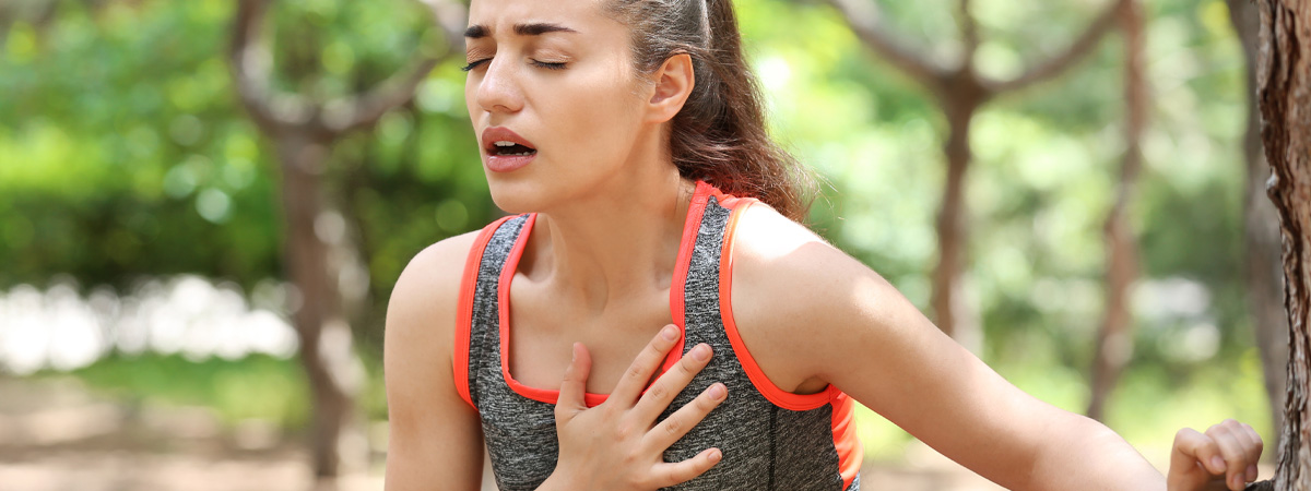Young woman in athletic wear holding her hand against her heart in pain.
